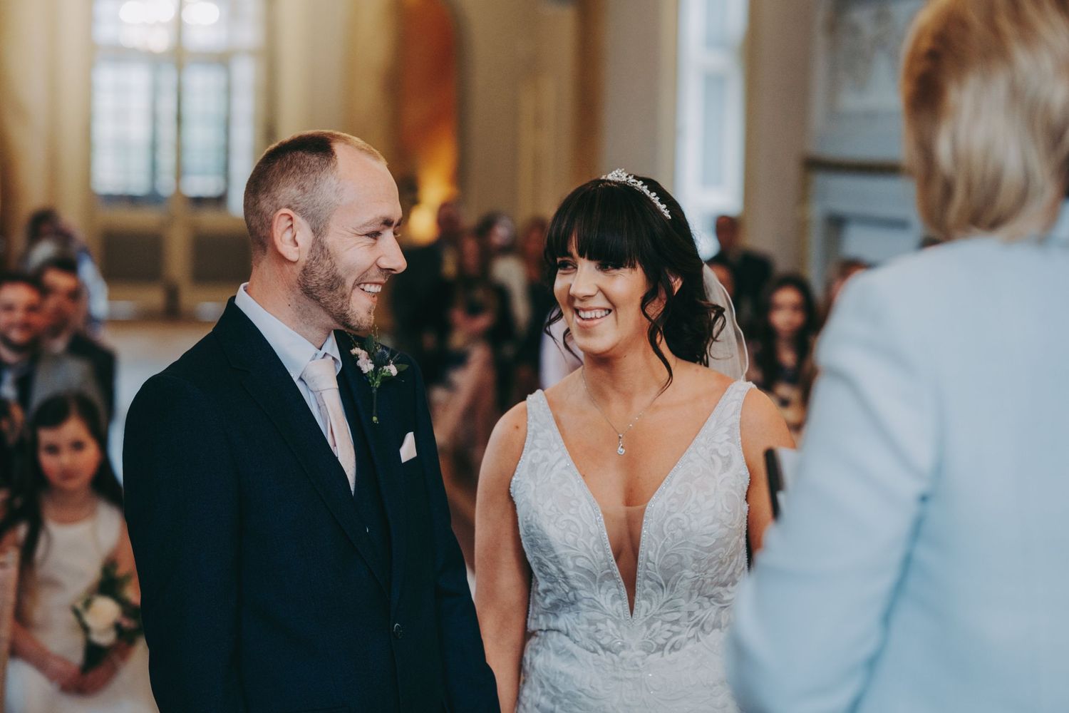 A couple shares a joyful moment during their wedding ceremony in an elegant hall.