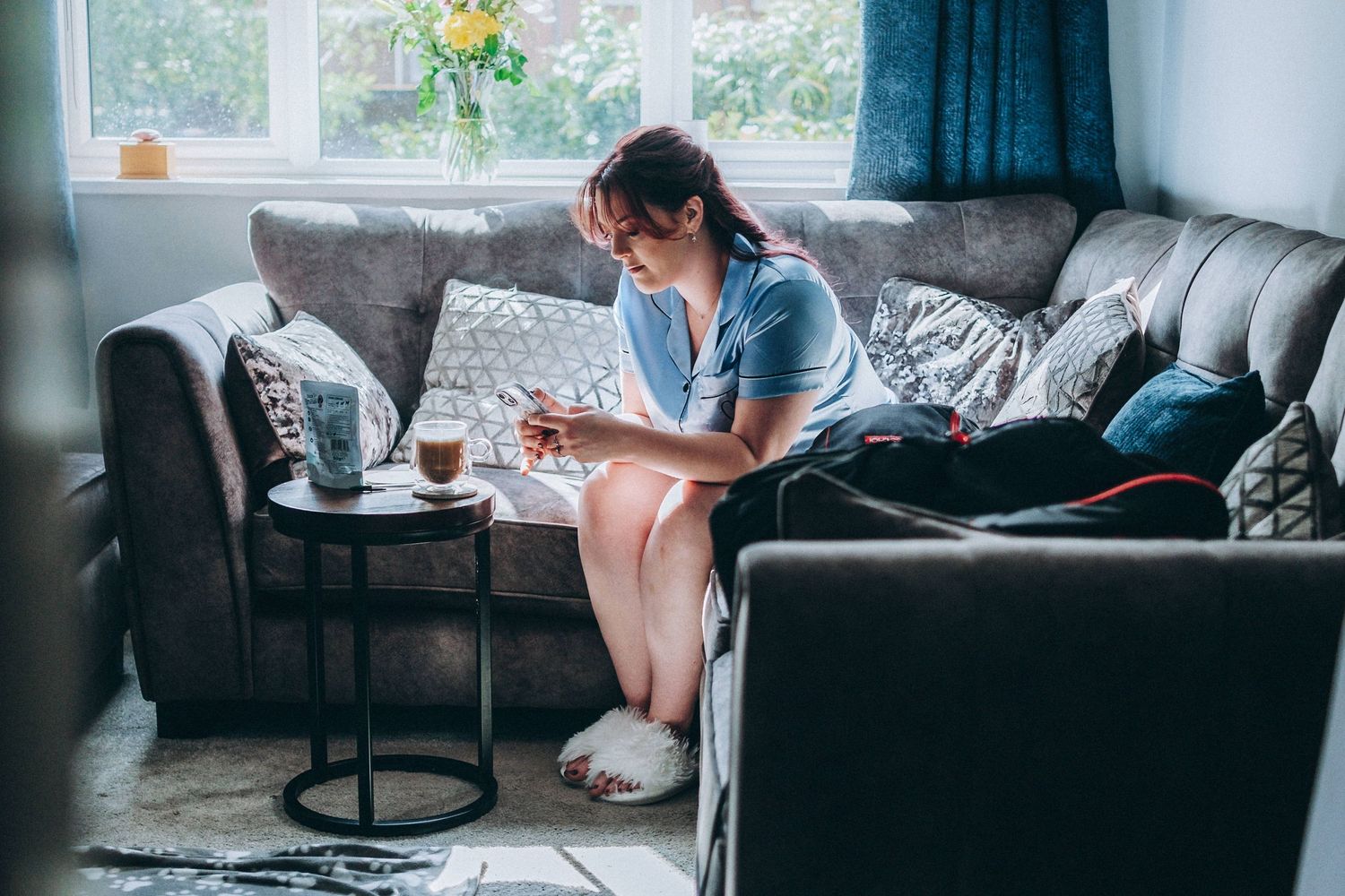 A cozy scene of relaxation on a grey sofa with a coffee and book on a side table.