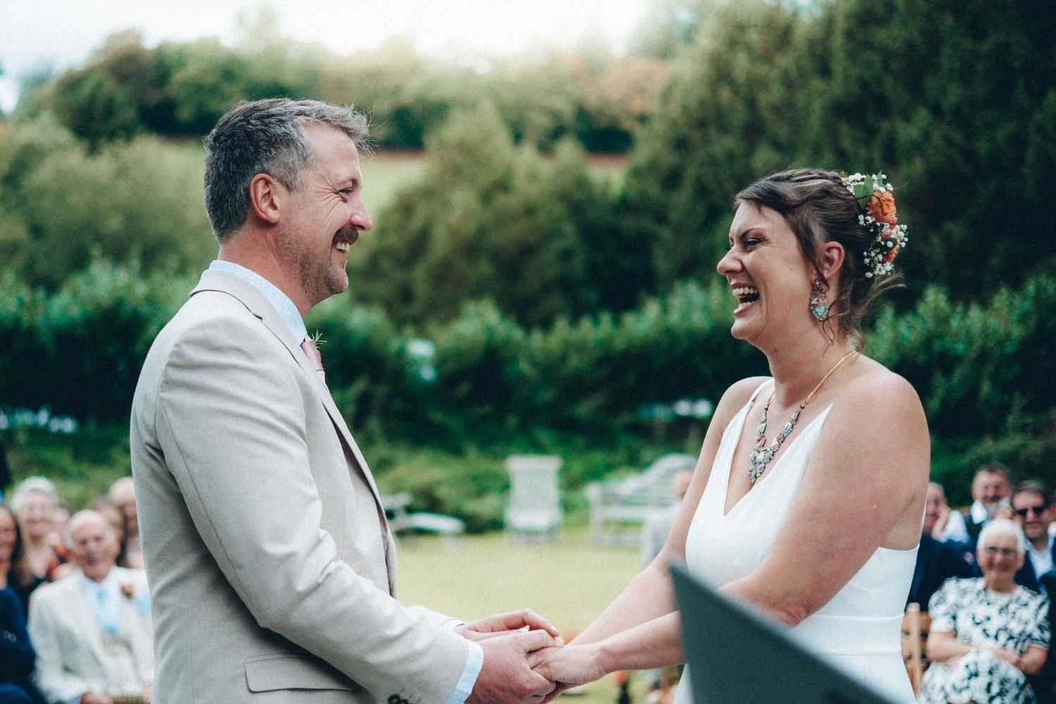 A couple shares a heartfelt laugh during their outdoor wedding ceremony.