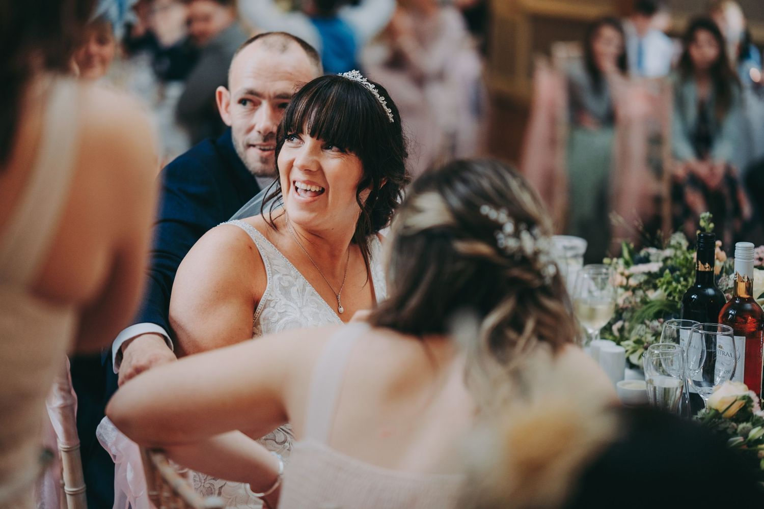 Wedding guests share an enthusiastic moment of laughter during reception celebration.