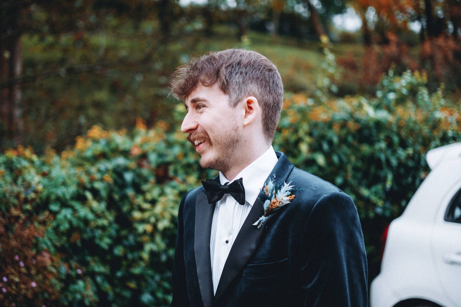 Outdoor portrait in formal attire against autumn foliage background.