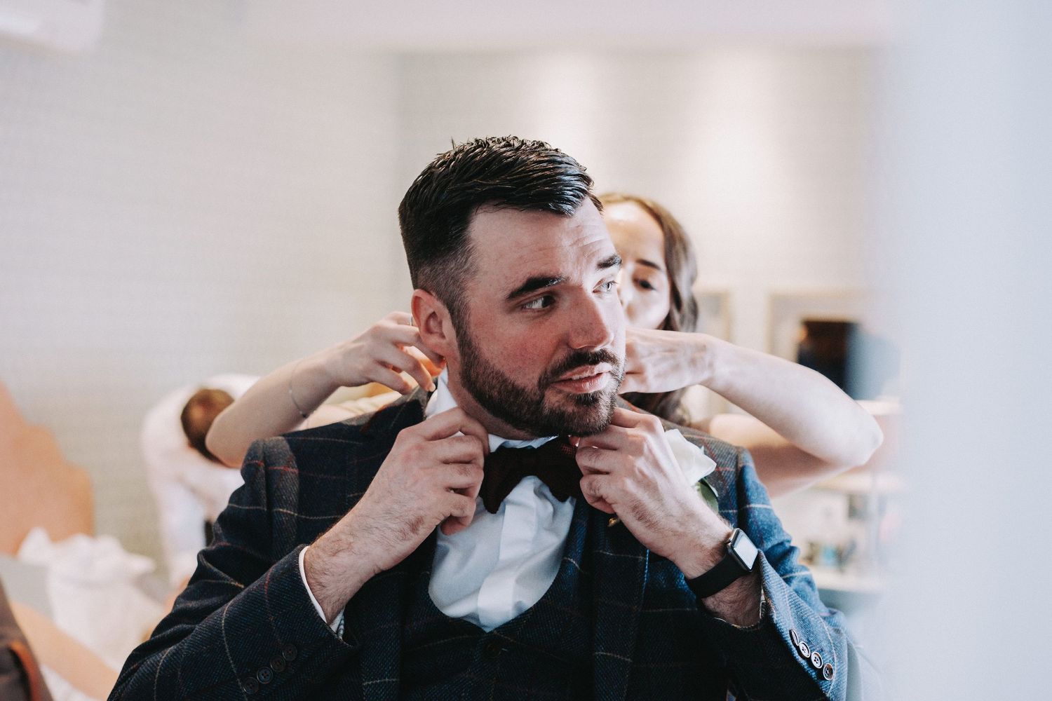 Someone adjusts their bowtie while getting ready for a formal event.