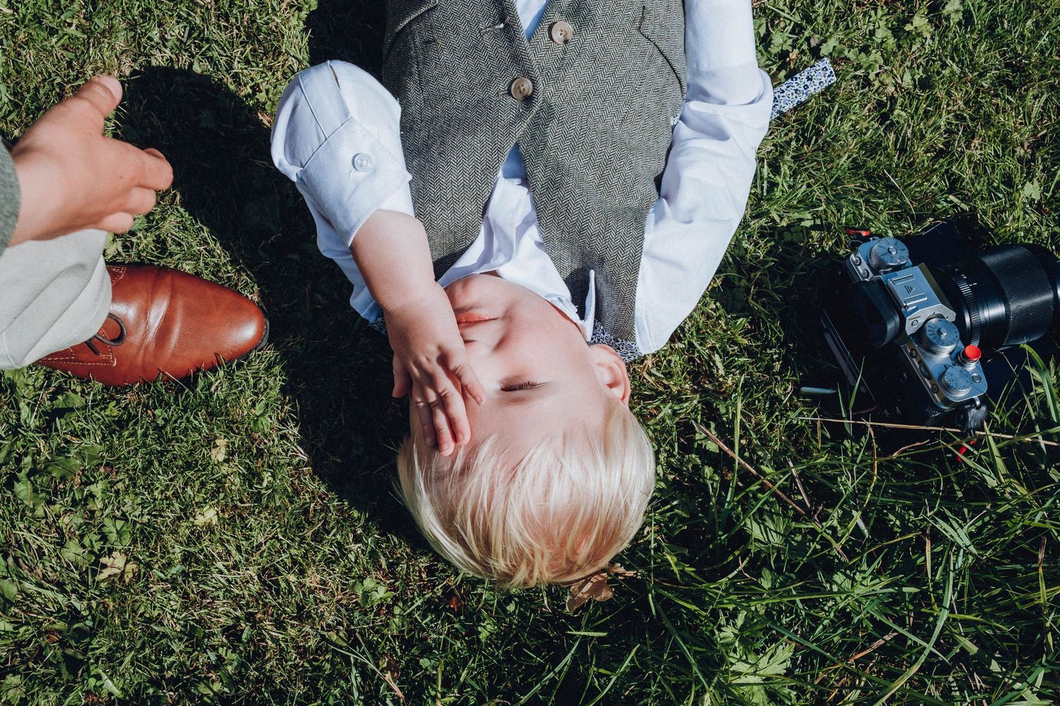 Young guests playing and crawling on grassy ground during an outdoor gathering.