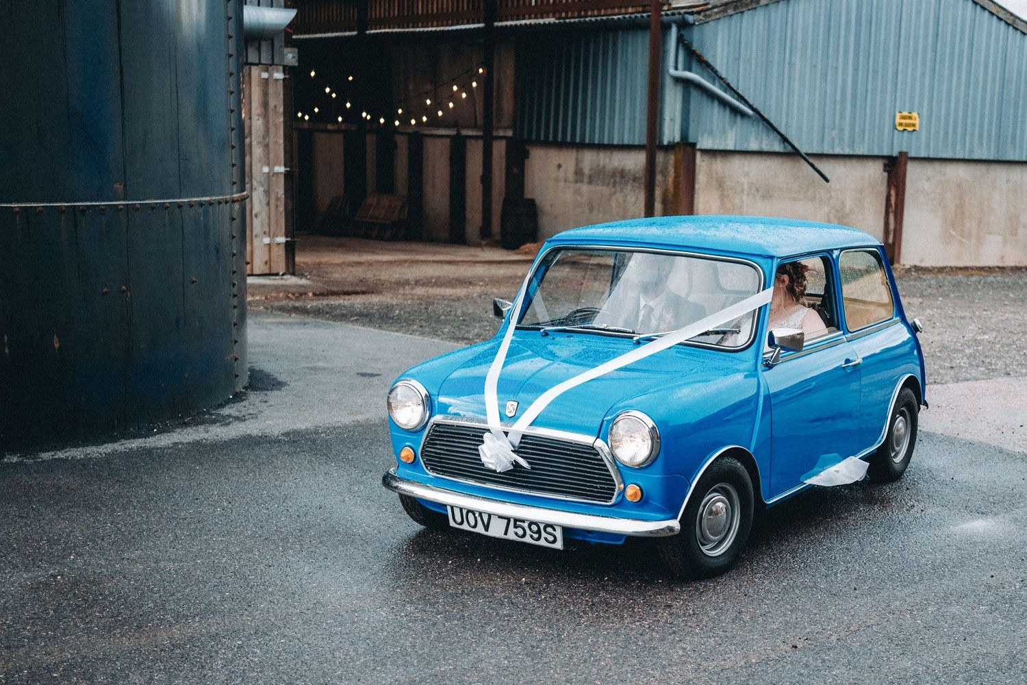 Classic blue Mini Cooper decorated with white ribbons for a wedding.