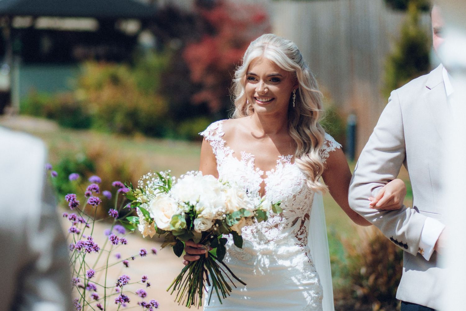 Romantic outdoor wedding ceremony with floral decorations and white seating arrangements.