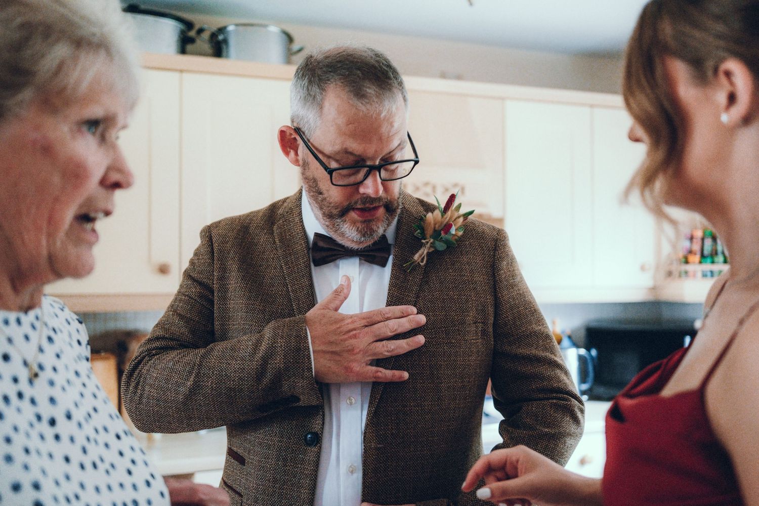 Wedding party members interacting in a casual indoor setting wearing formal attire.