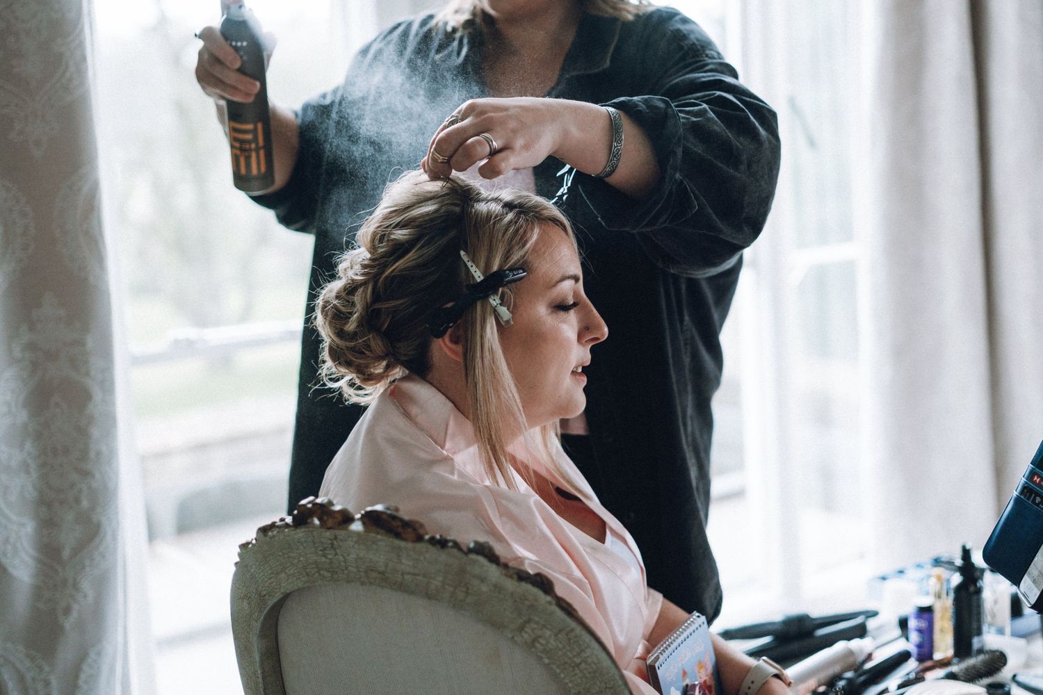 Professional hair styling session in progress with styling tools and products visible.
