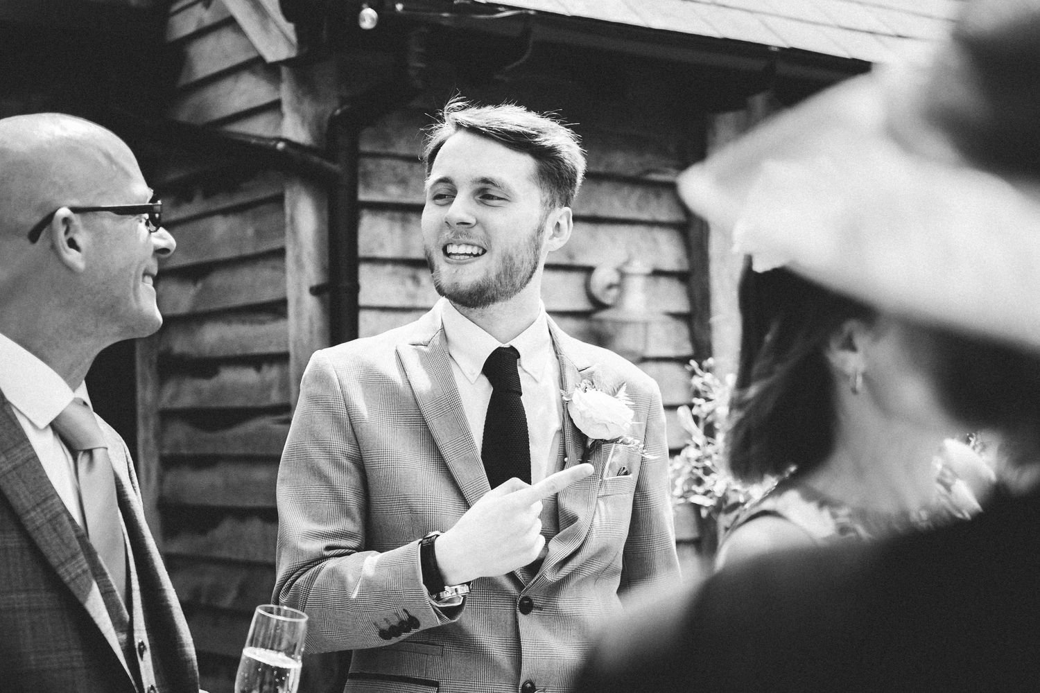 Joyful wedding celebration captured in black and white as guests share drinks and laughter.