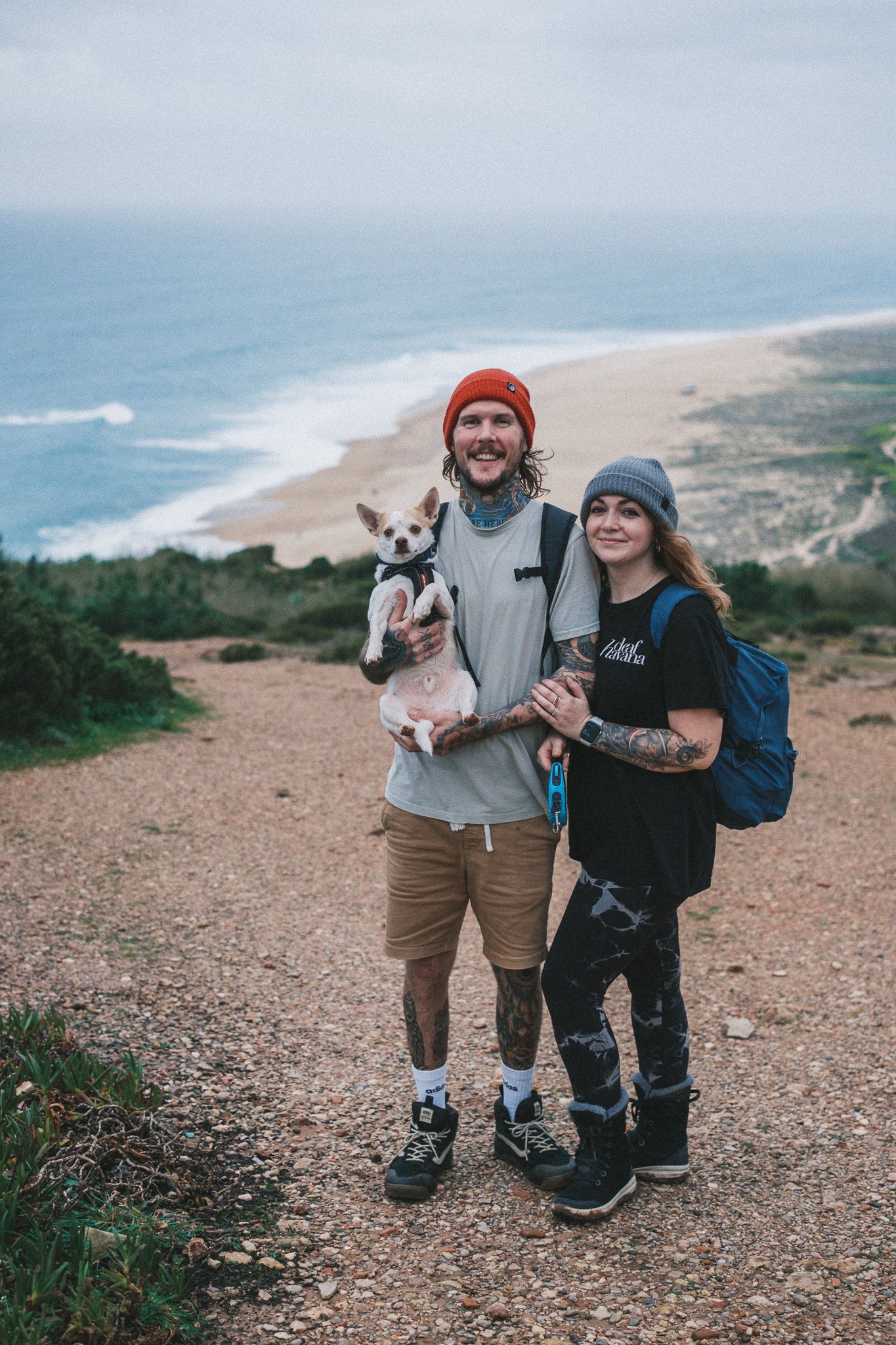 Couple with small dog enjoying scenic coastal hiking trail view.