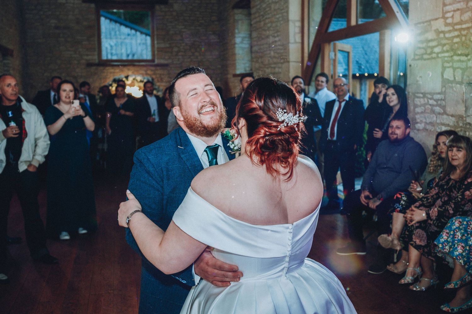 Couple shares their first dance at wedding reception in rustic stone venue.