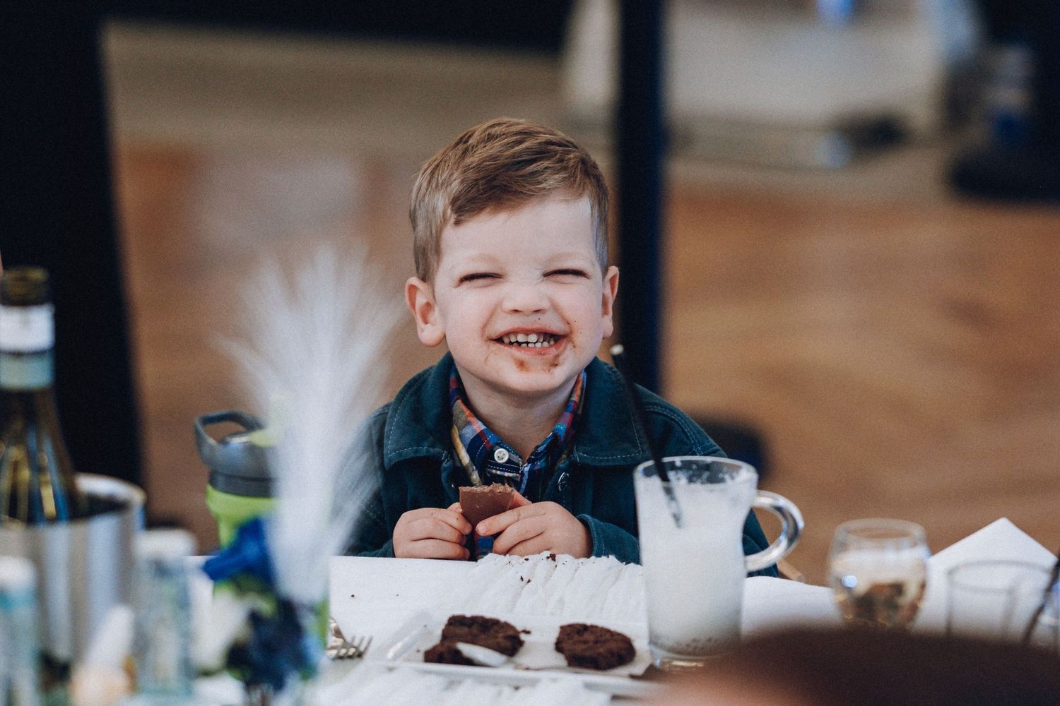 Child enjoying refreshments at a wedding reception with natural lighting.
