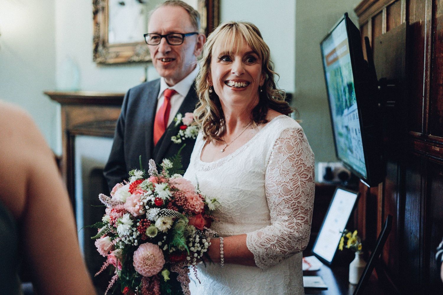 Wedding party members gathered near a wooden staircase with pink floral bouquets.