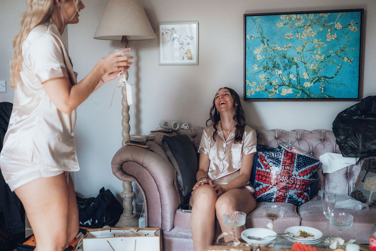 Wedding party members relax in a casual indoor setting with decorative art on the walls.