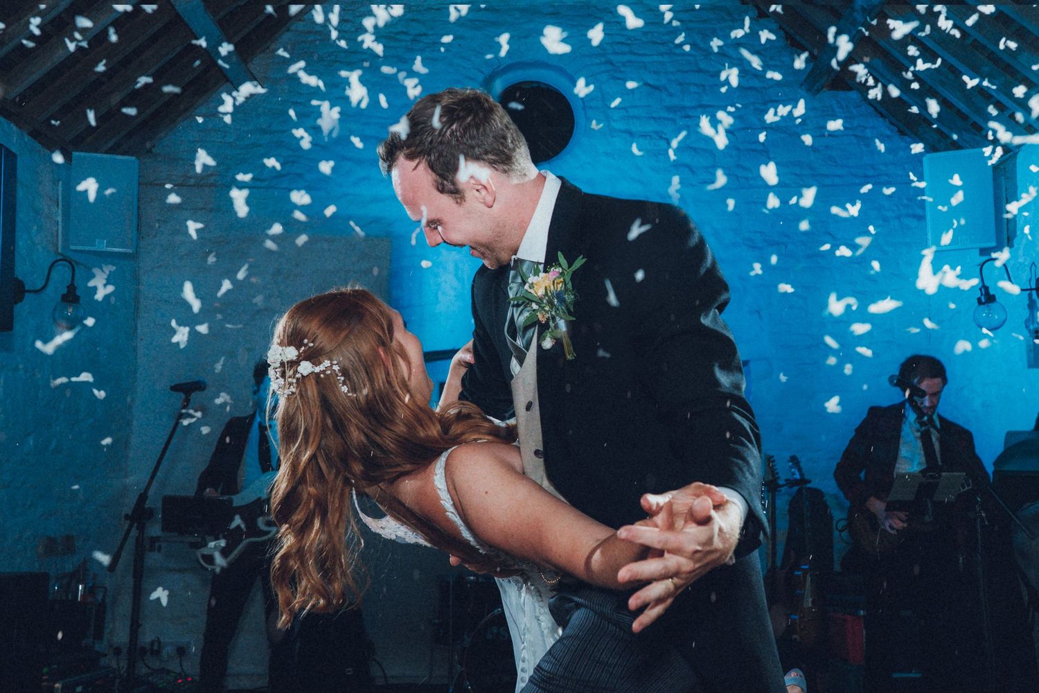 Wedding celebration with confetti falling against vibrant blue lighting at reception venue.