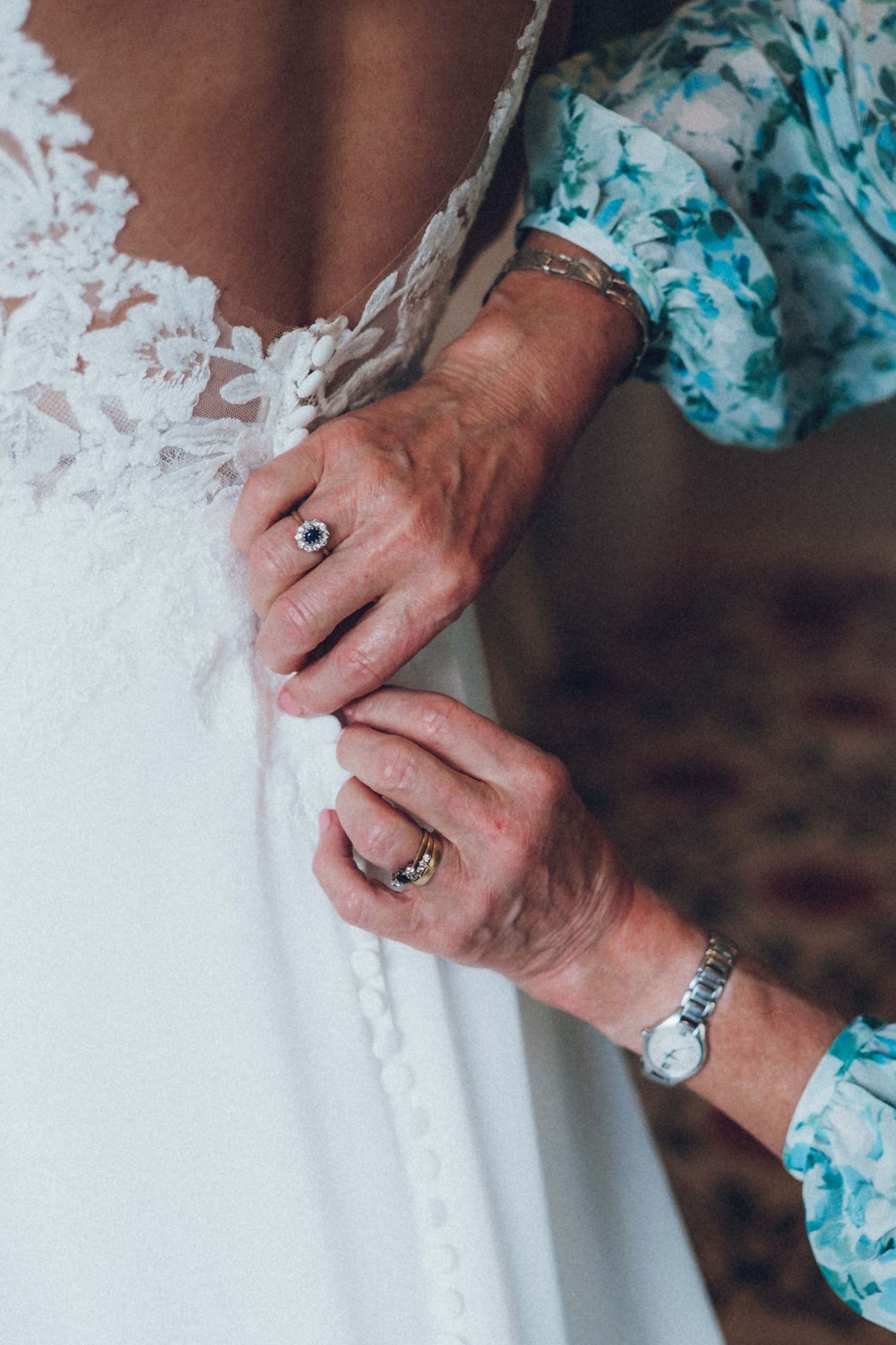 Detailed shot of hands with rings and watch working on wedding dress lace.