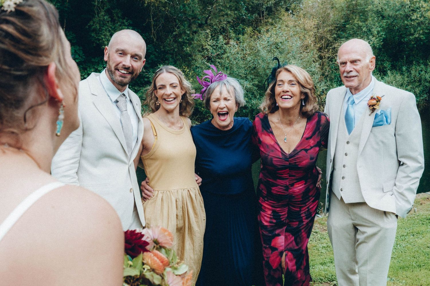 Wedding guests gather outdoors for group photos on a sunny afternoon.