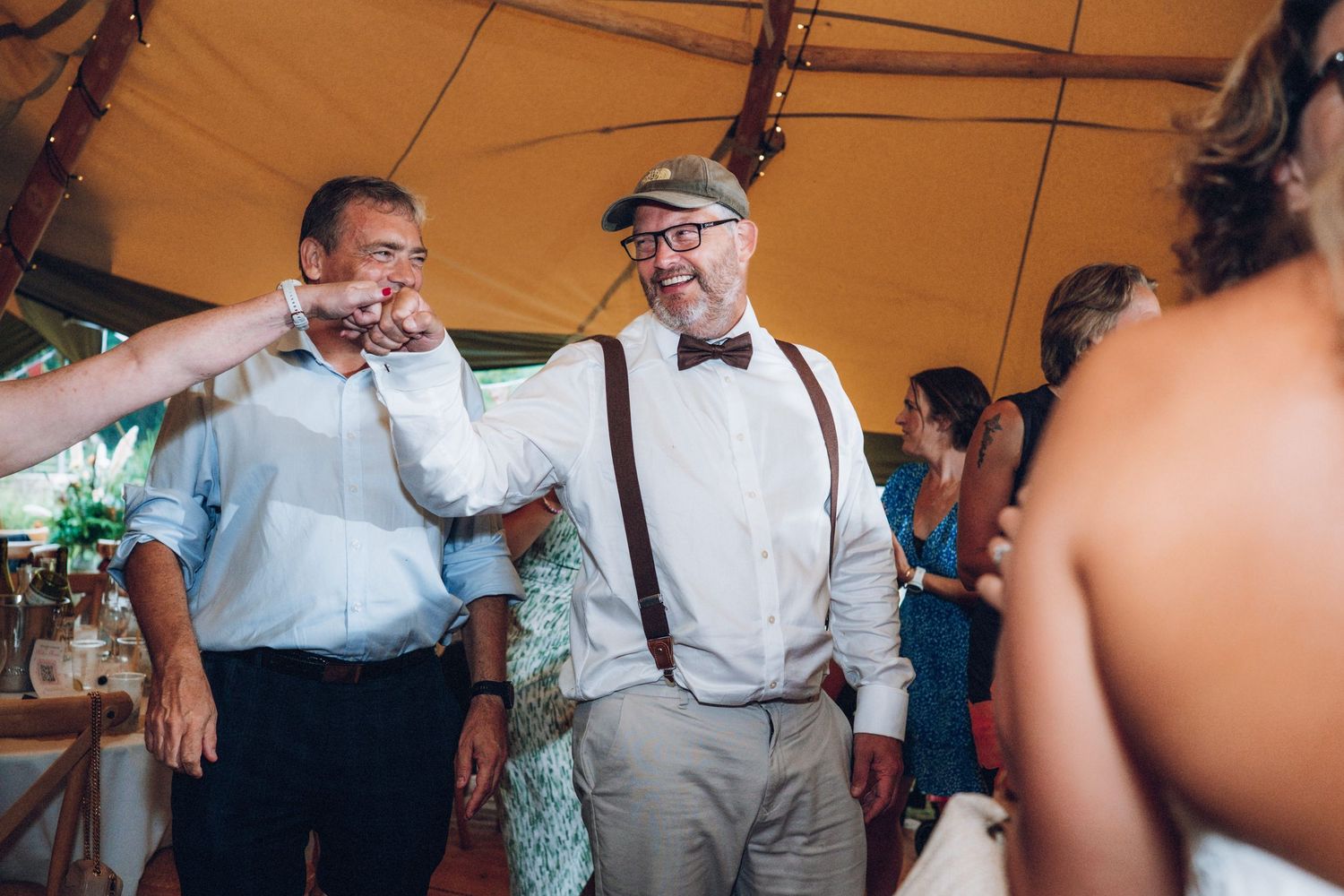 Wedding celebration in a rustic tent venue with guests dancing.