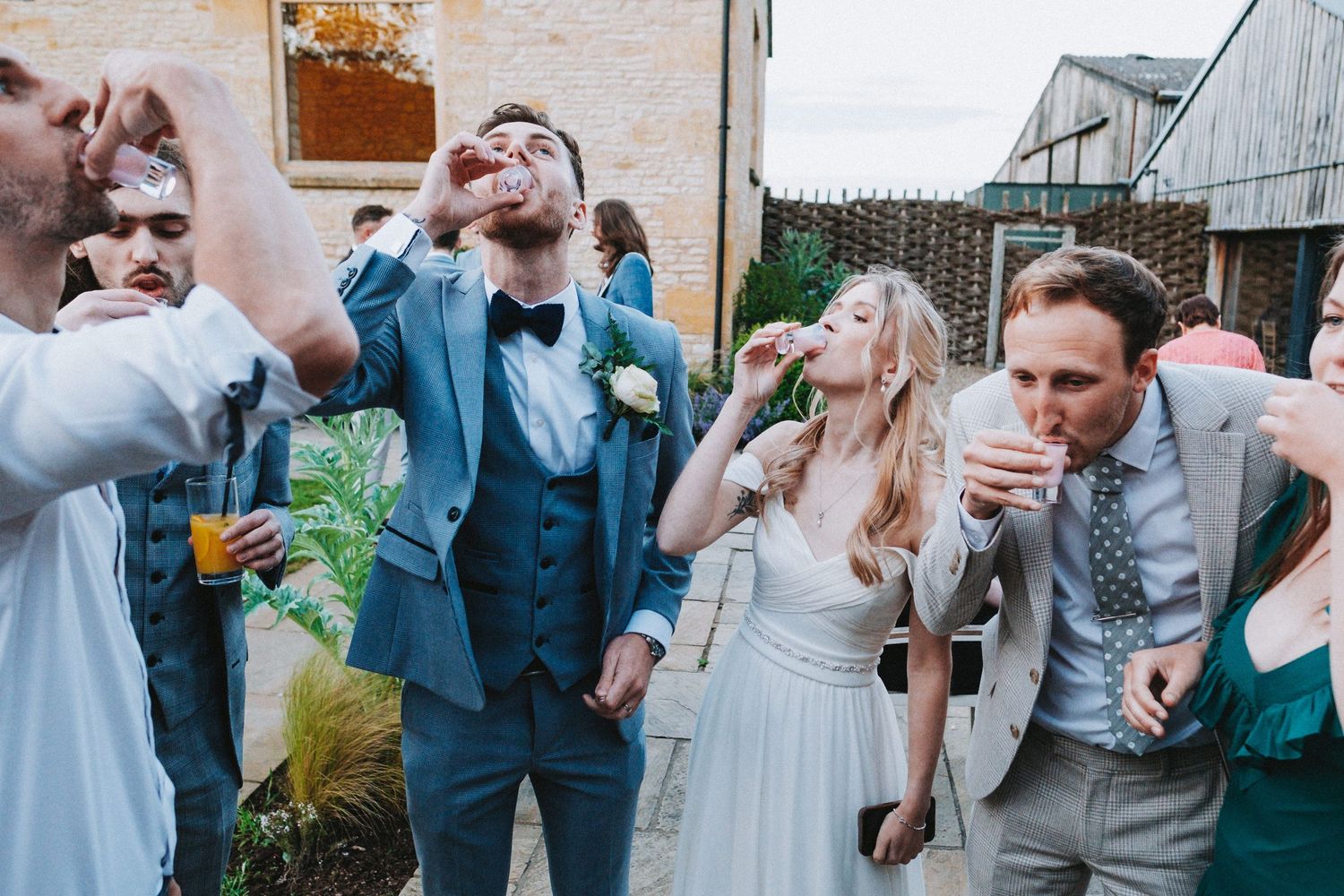 Wedding guests taking shots together at an outdoor reception celebration.