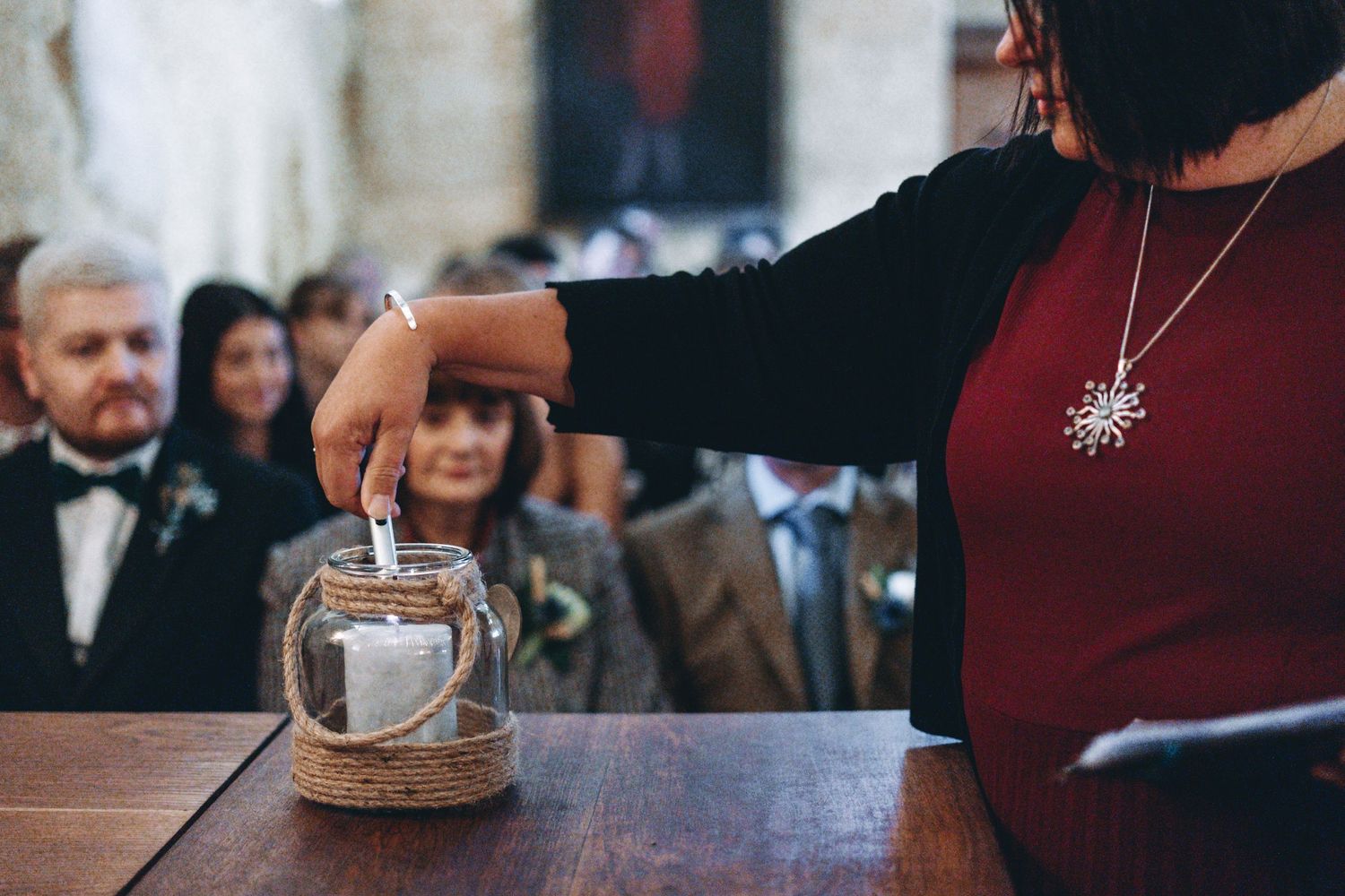 A hand pours a drink into a glass lantern at an elegant event.