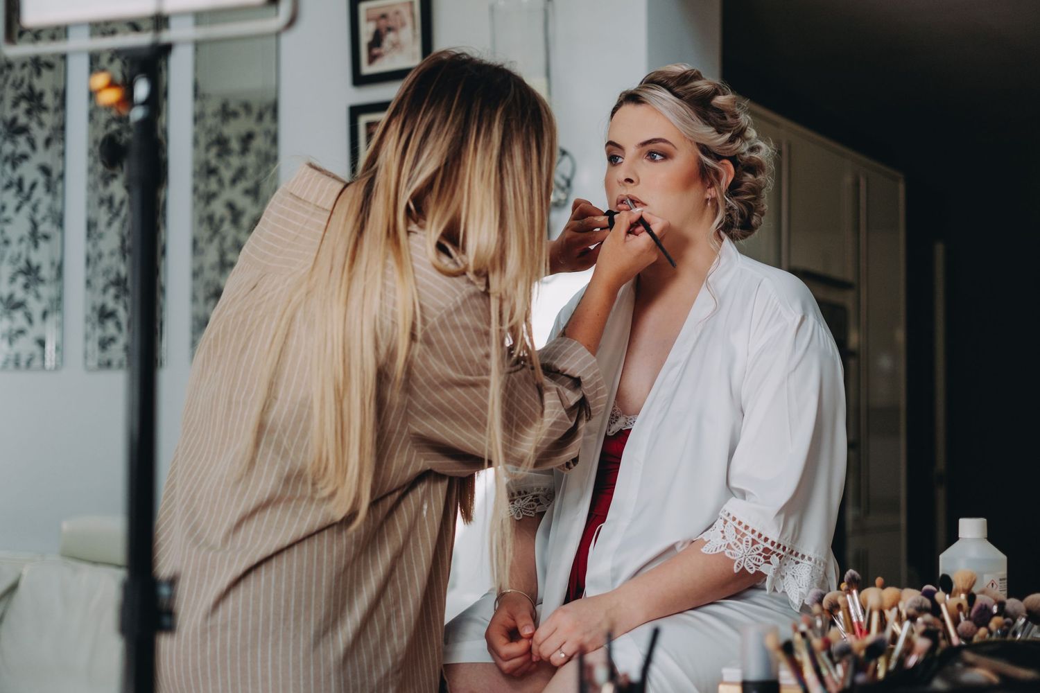 Getting ready scene with makeup application during wedding preparations.