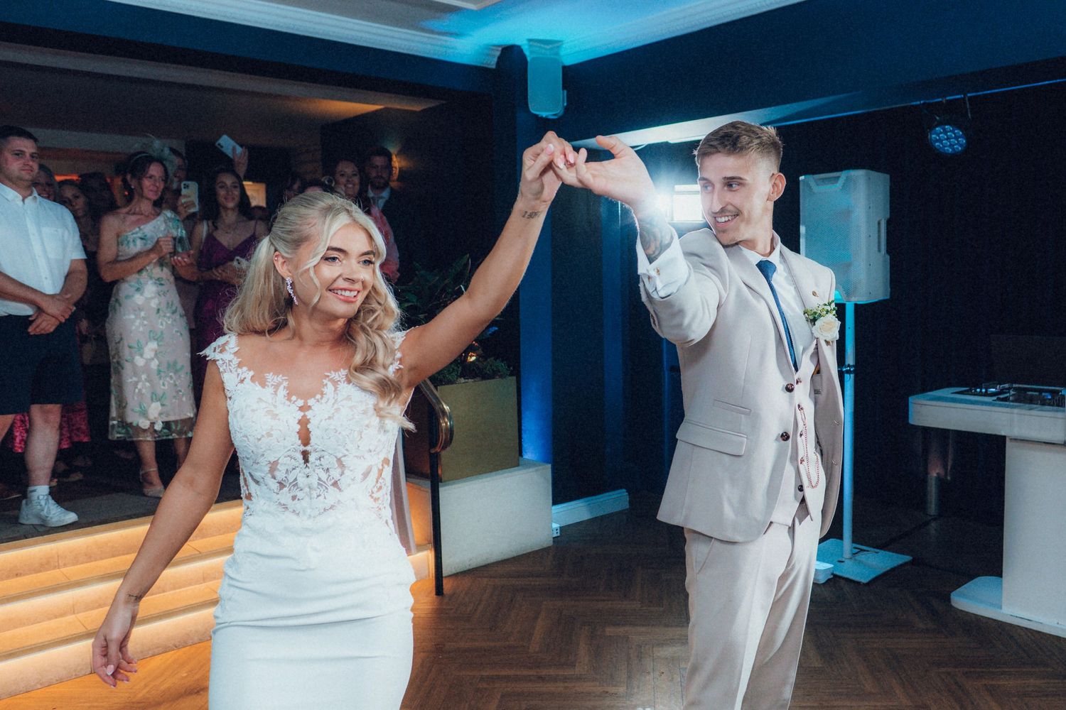 Newlyweds dancing and twirling on wooden dance floor during reception celebration.