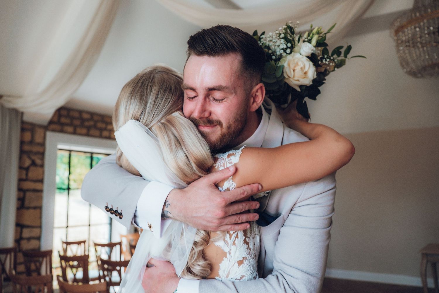 Tender wedding day embrace captured in natural window light.