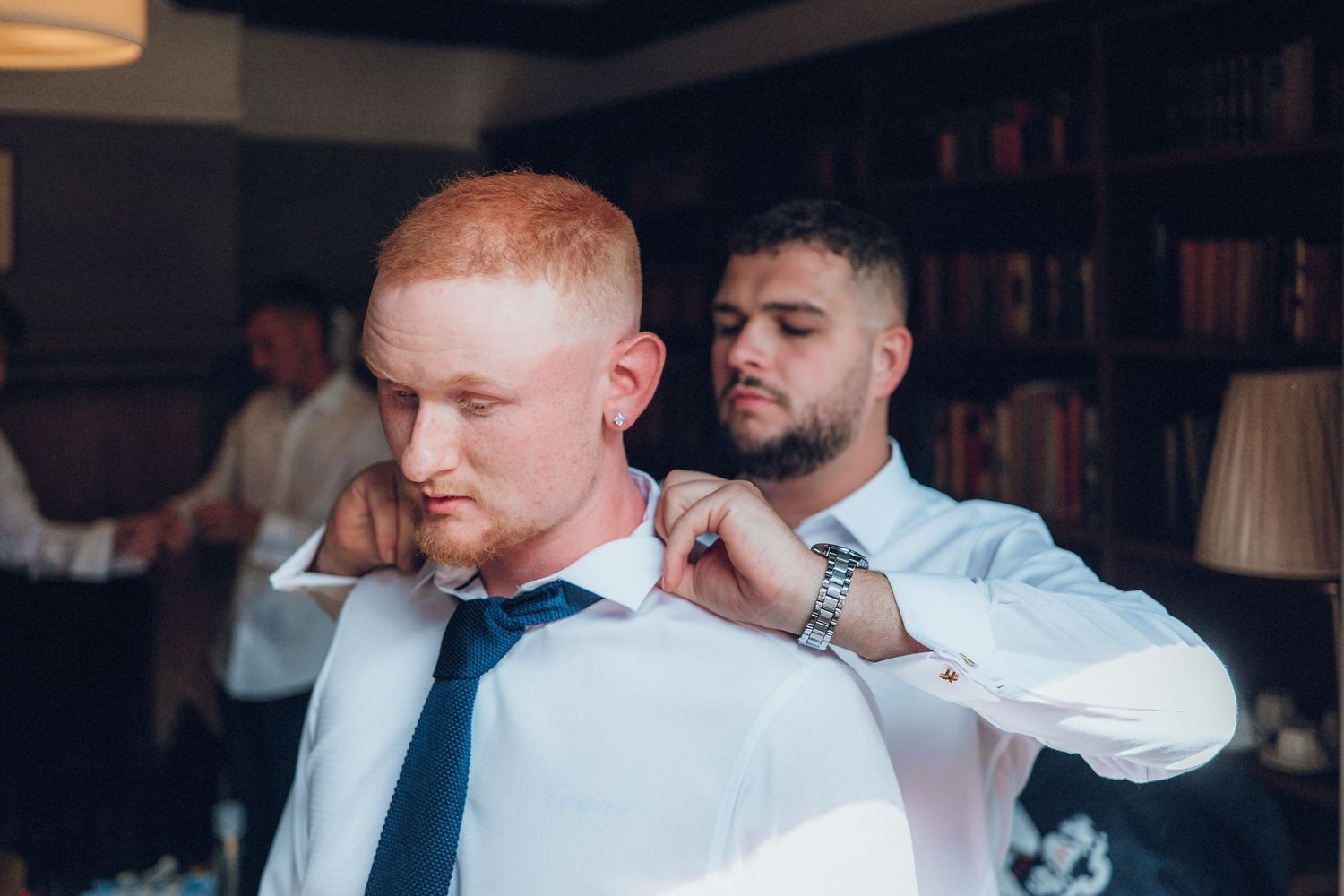Men in white shirts and ties preparing for a formal event.