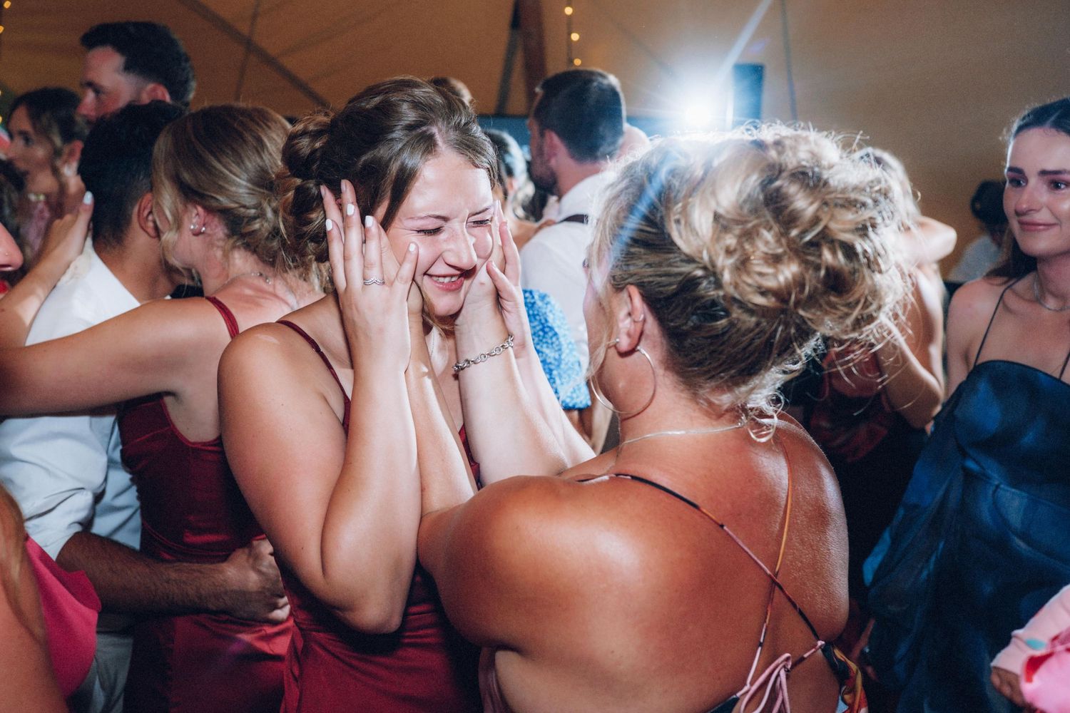 Wedding guests dancing and celebrating joyfully at a reception under string lights.