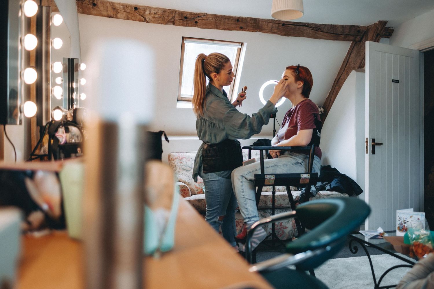 Behind-the-scenes preparation in a dressing room with vanity mirrors and bright lights.