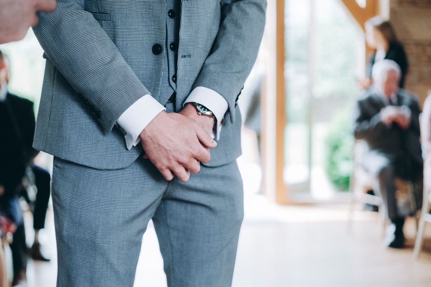 Detail shot of groom in gray suit adjusting cufflinks before ceremony.