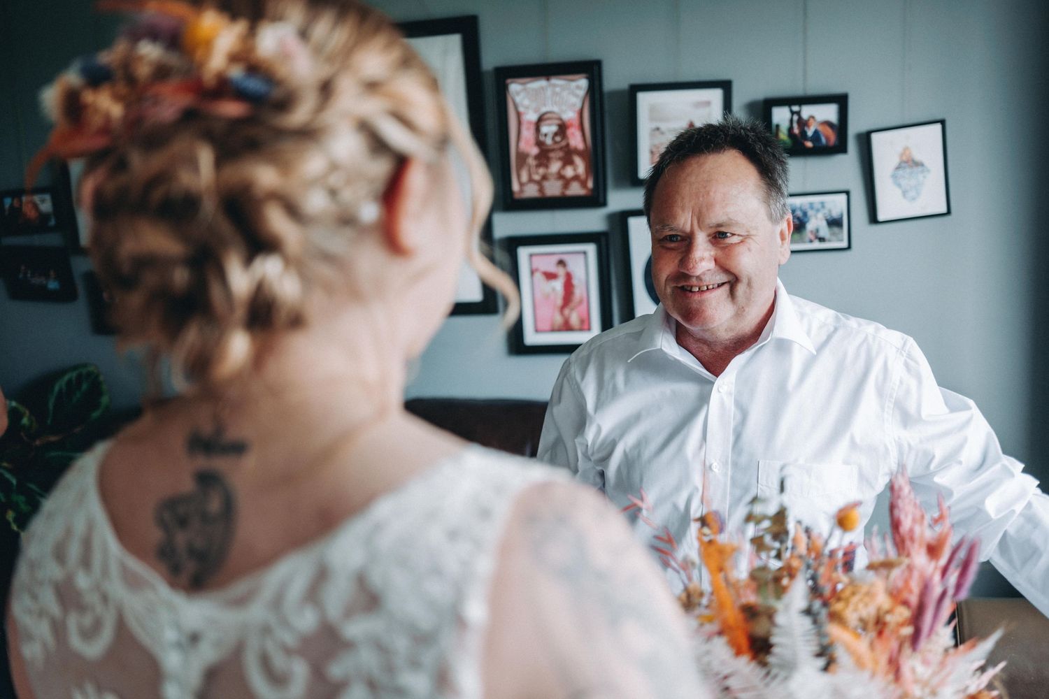 Bride and father share a joyful wedding moment with photography and decor visible in the background.