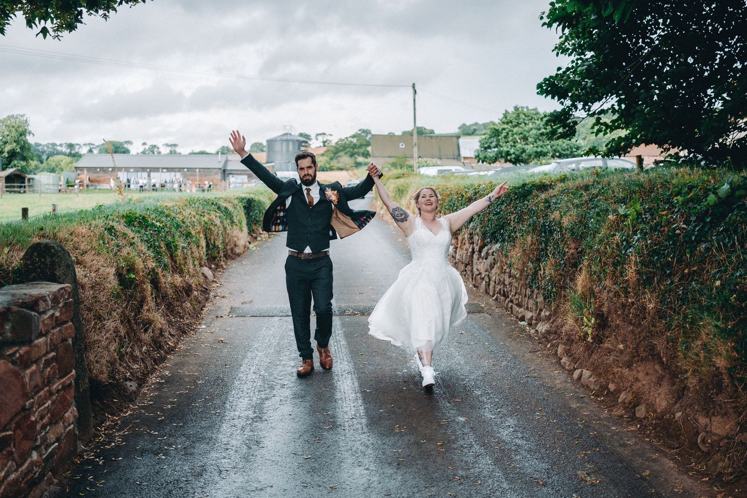 A carefree moment on a wet country road as a couple celebrates their wedding day.