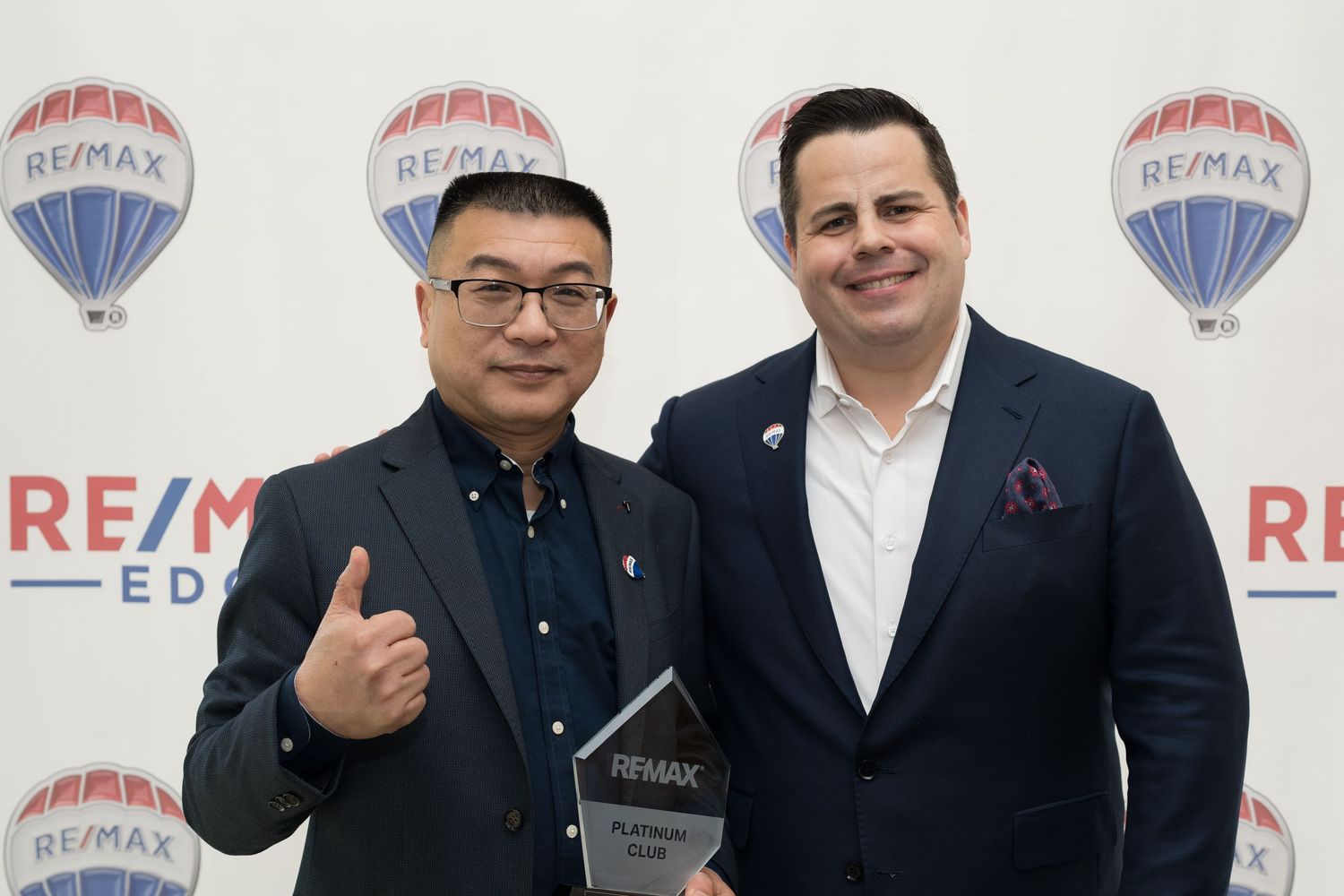 Two RE/MAX Edge male agents celebrate with platinum award at RE/MAX event.