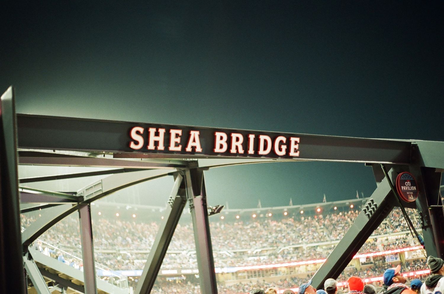 Shea Bridge sign illuminated at Citi Field stadium during a New York Mets night game.