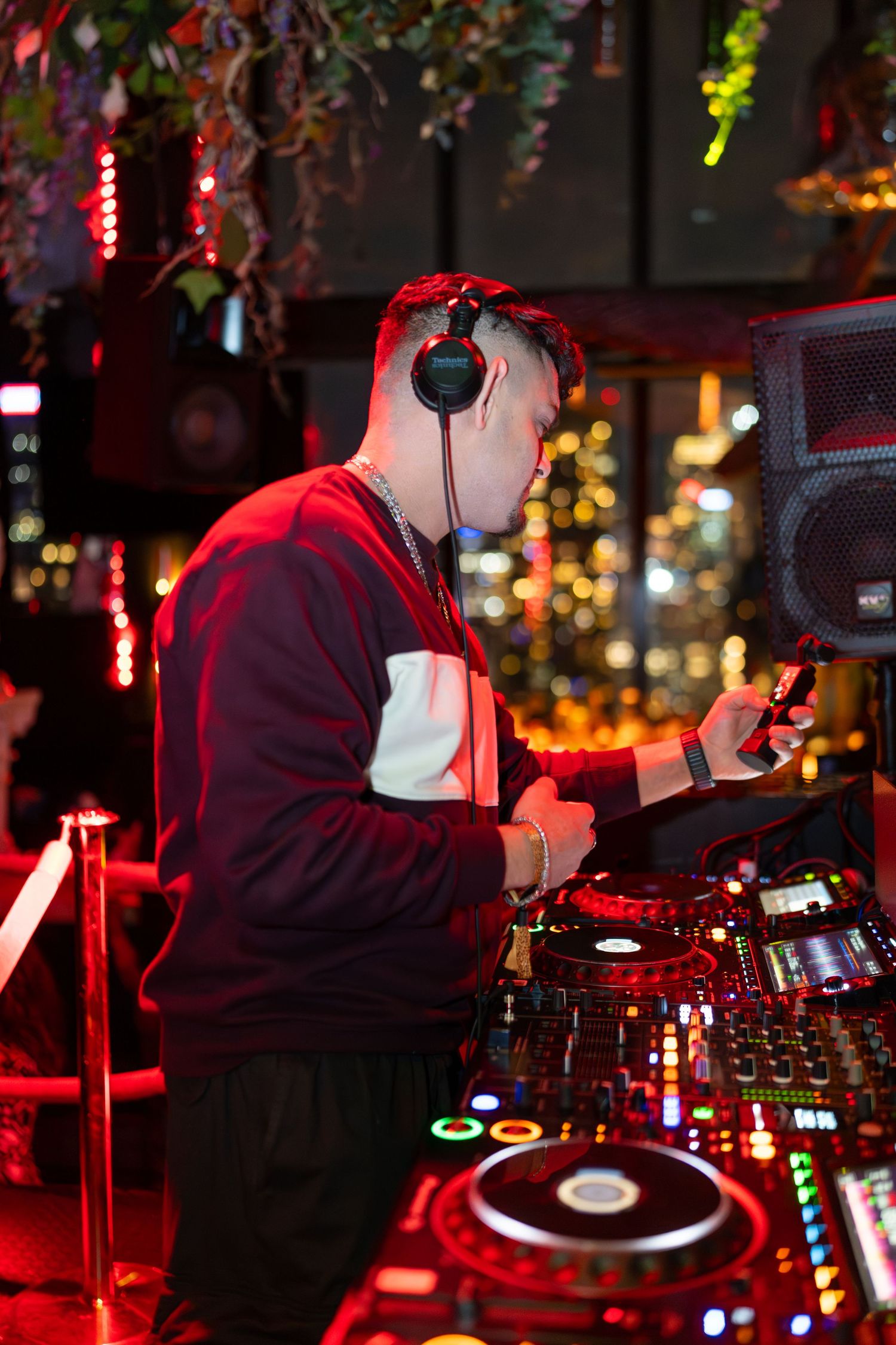 DJ mixing music at a vibrant nightclub with colorful bokeh lights in the background.