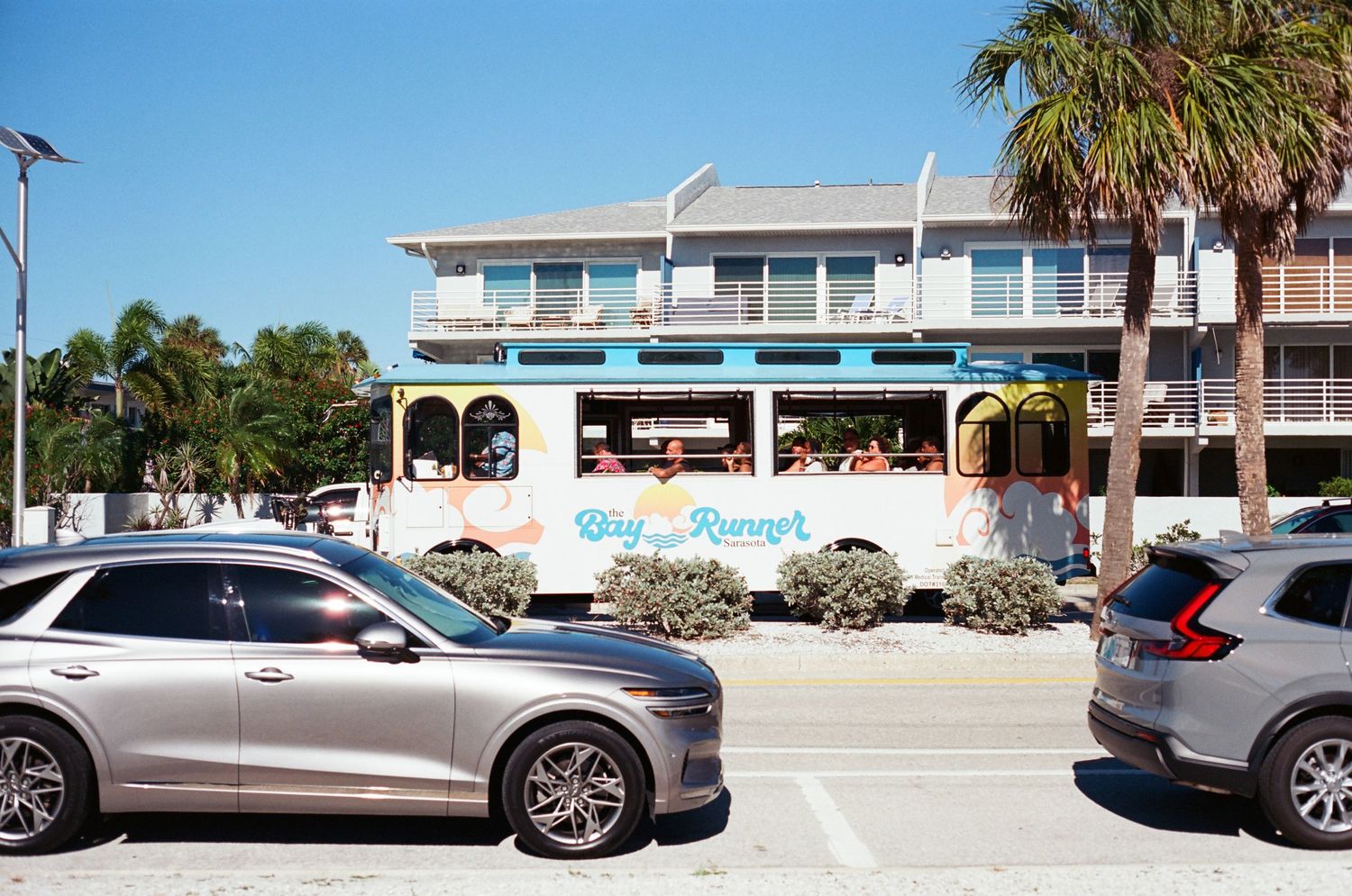 Colorful Big Burger trolley restaurant parked near SUVs in a sunny Florida beach town parking lot.
