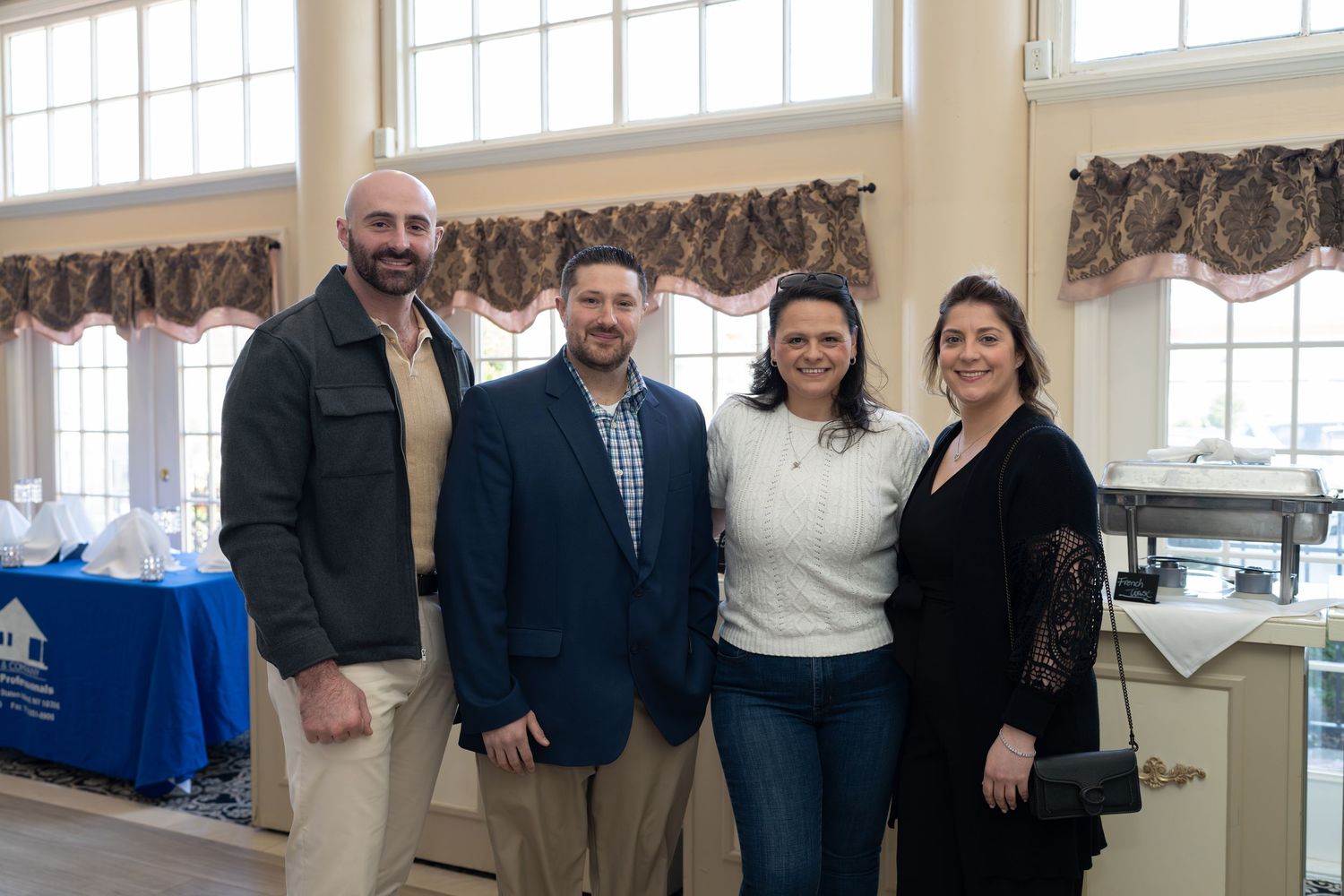 Four professionals smiling together at a RE/MAX Edge real estate networking event in an elegant venue.
