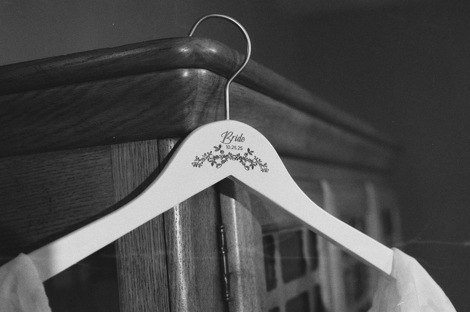 Black and white photo of a white wooden bride hanger on a wooden dresser.