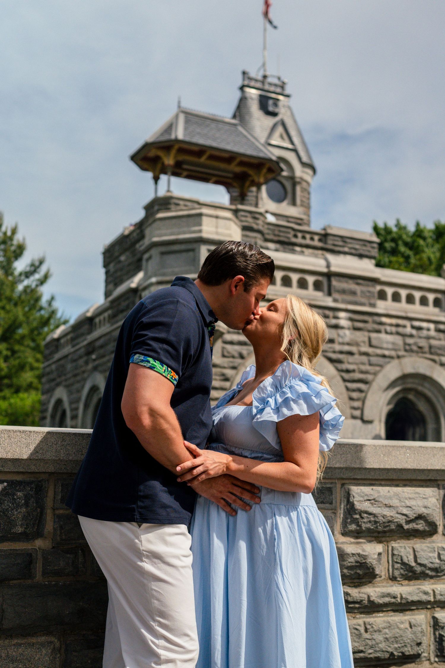 Couple kissing in front of Belvedere Castle in Central Park on a sunny day.