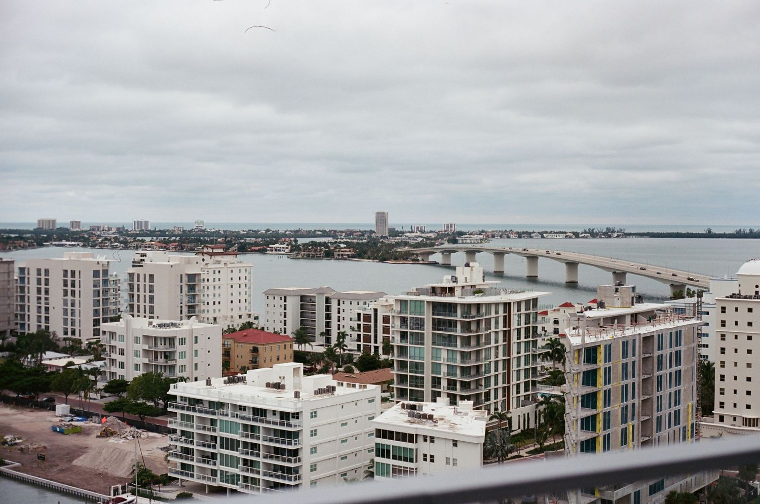 Aerial view of Miami Beach cityscape with waterfront buildings and bridge over blue bay waters.