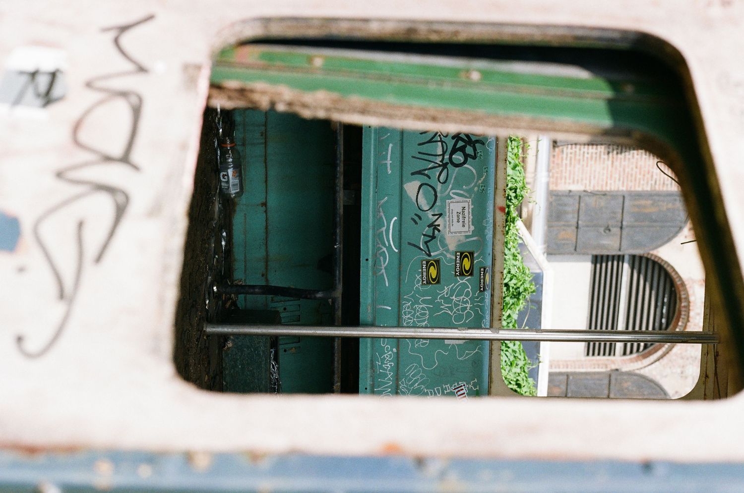 Graffiti-covered urban structure with green door visible through rectangular opening in wall.