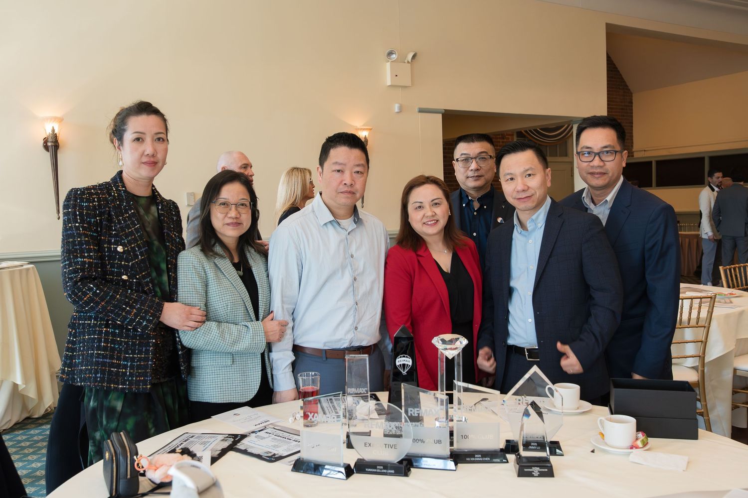 Group of seven RE/MAX Edge realtors pose with crystal awards on table at recognition luncheon.