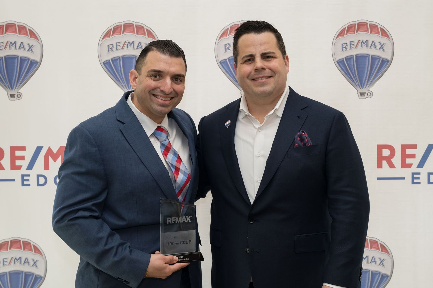 Two men hold RE/MAX award trophy at Edge awards ceremony.