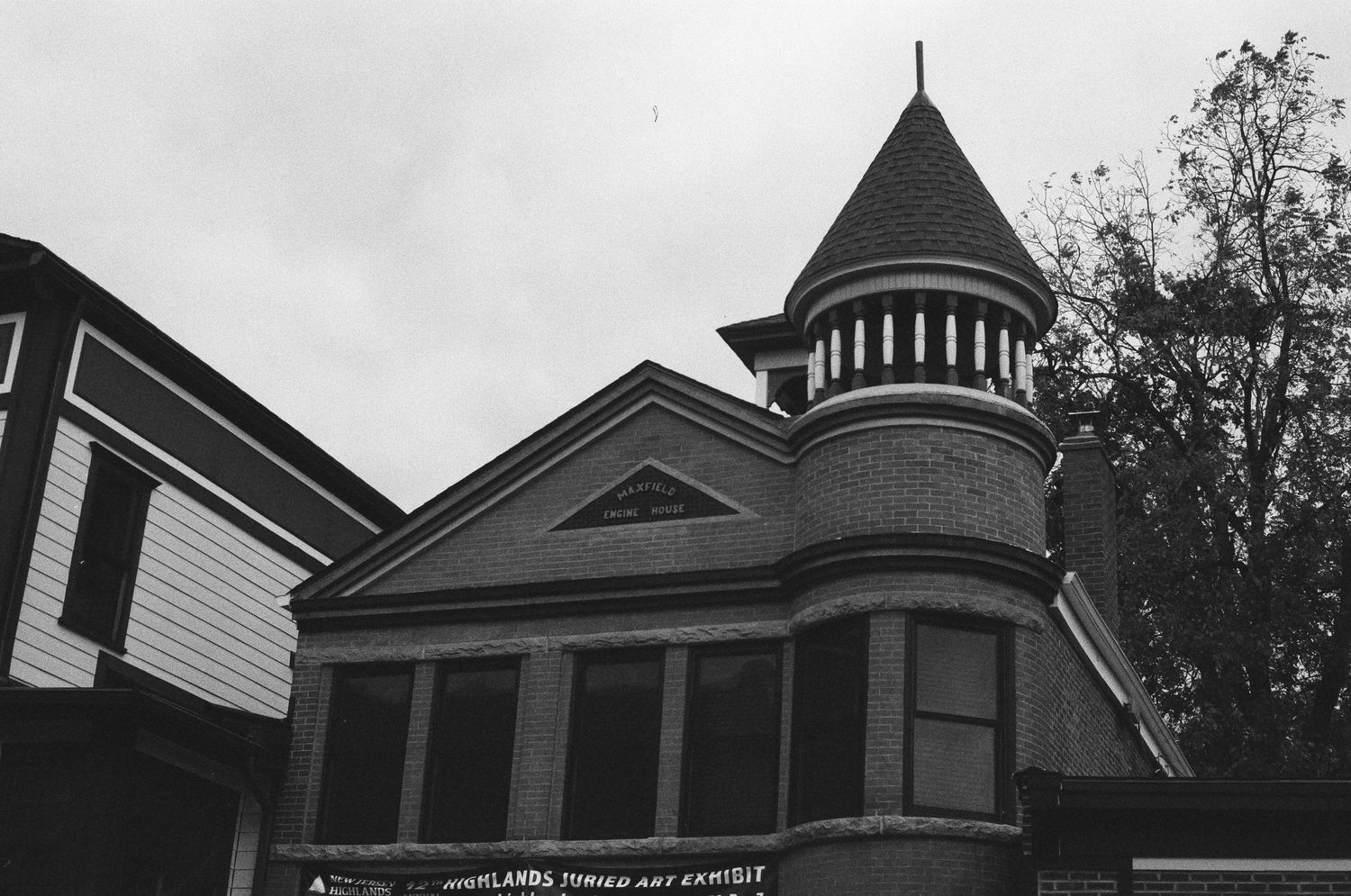 Black and white photo of a historic Victorian brick building with a conical tower and ornate architectural details.
