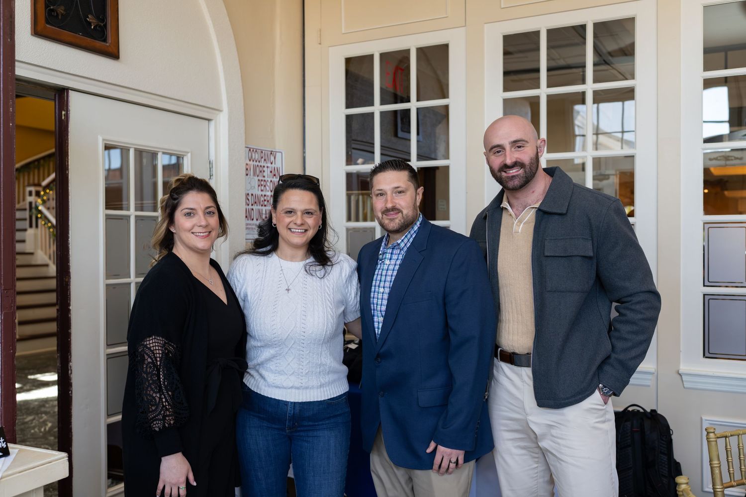 Two couples posing together at a RE/MAX Edge real estate business event near French doors.