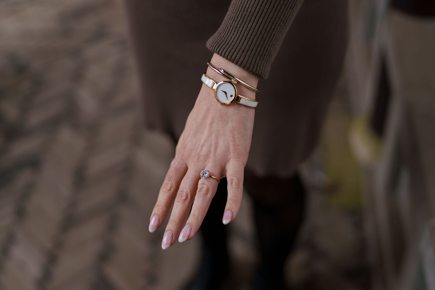 Close-up of woman's hand showcasing a delicate engagement ring and elegant wrap wrist watch.