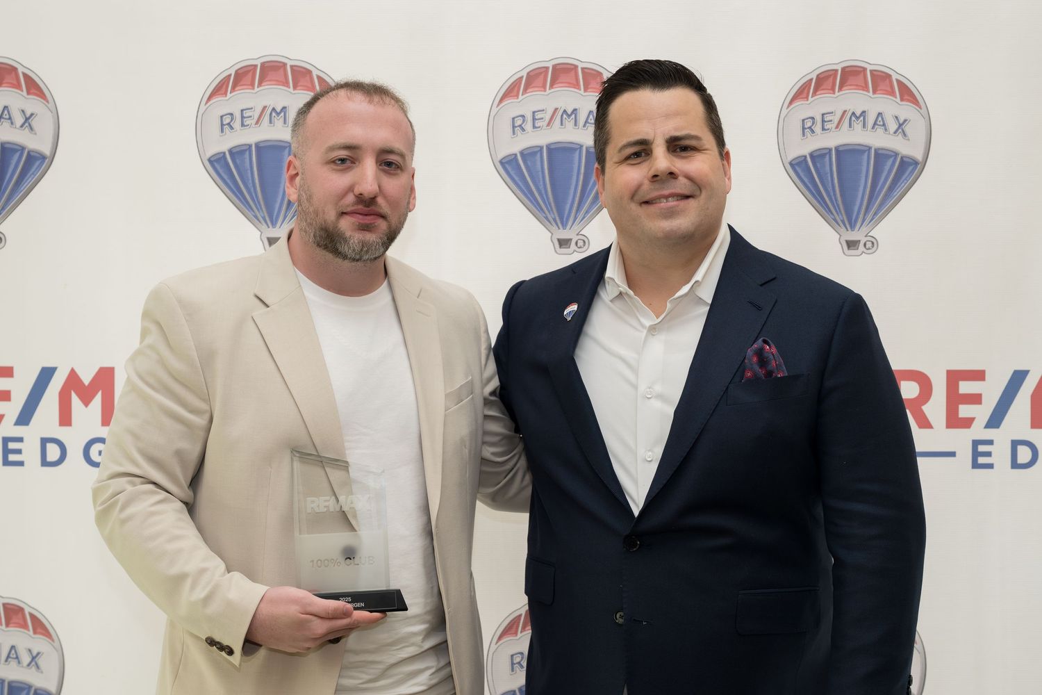 Two men pose with award at RE/MAX Edge real estate event.