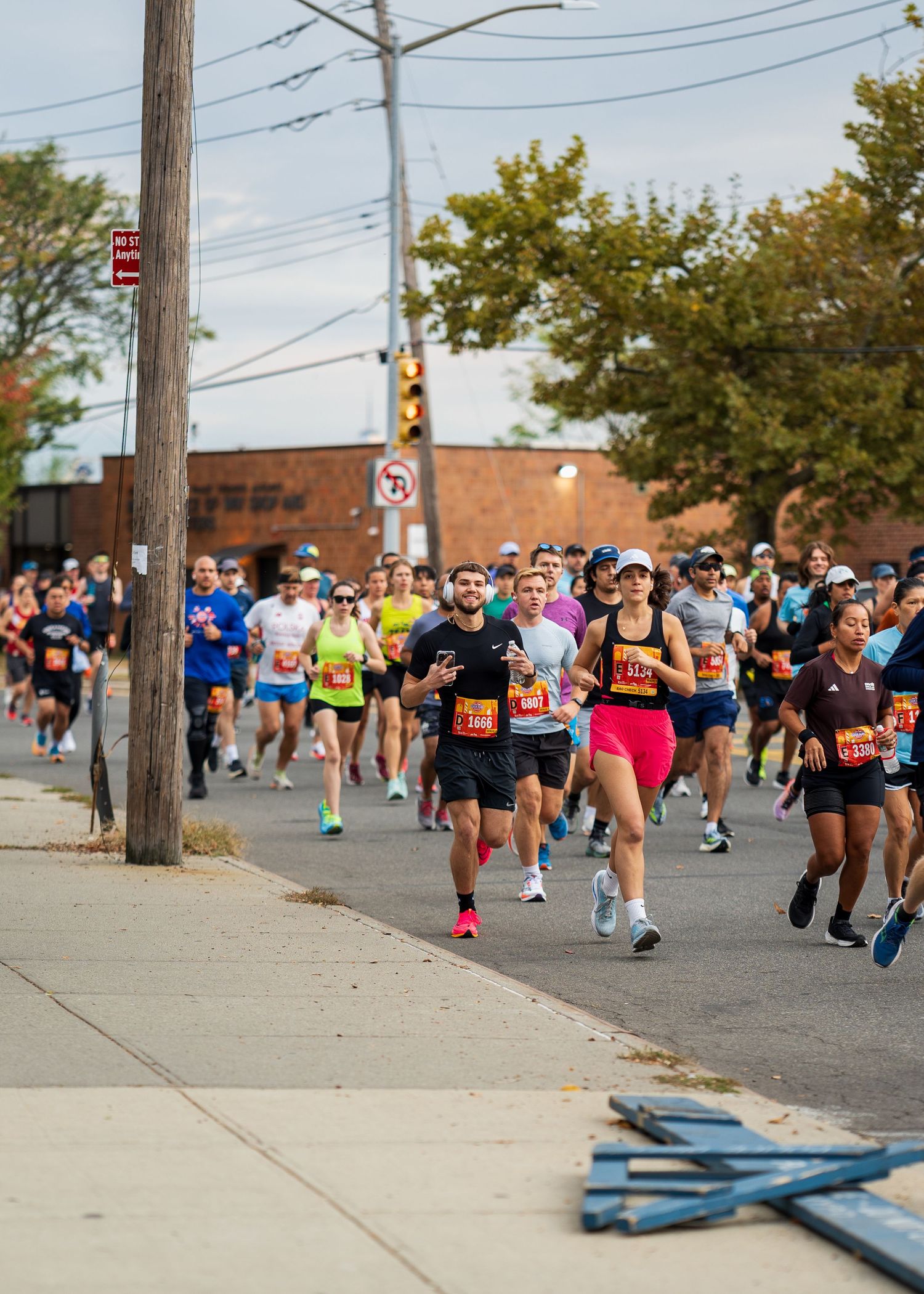 Large group of runners with race bibs competing in an outdoor street marathon.