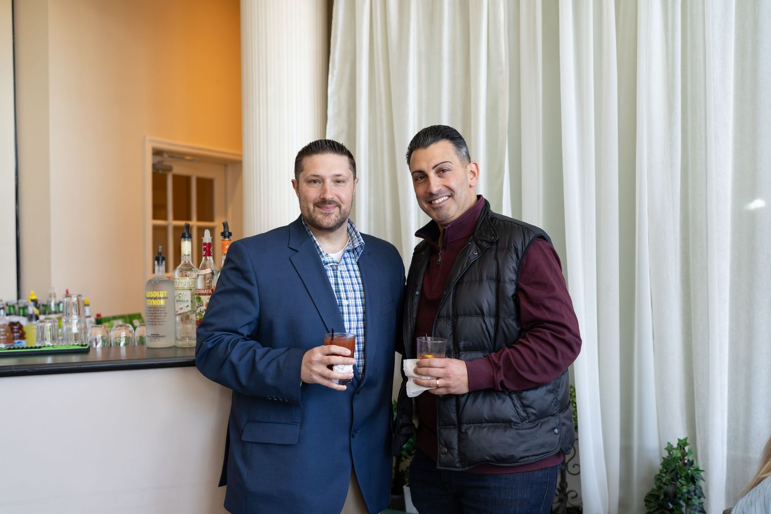 Two men in business casual attire smiling at a RE/MAX Edge real estate reception.