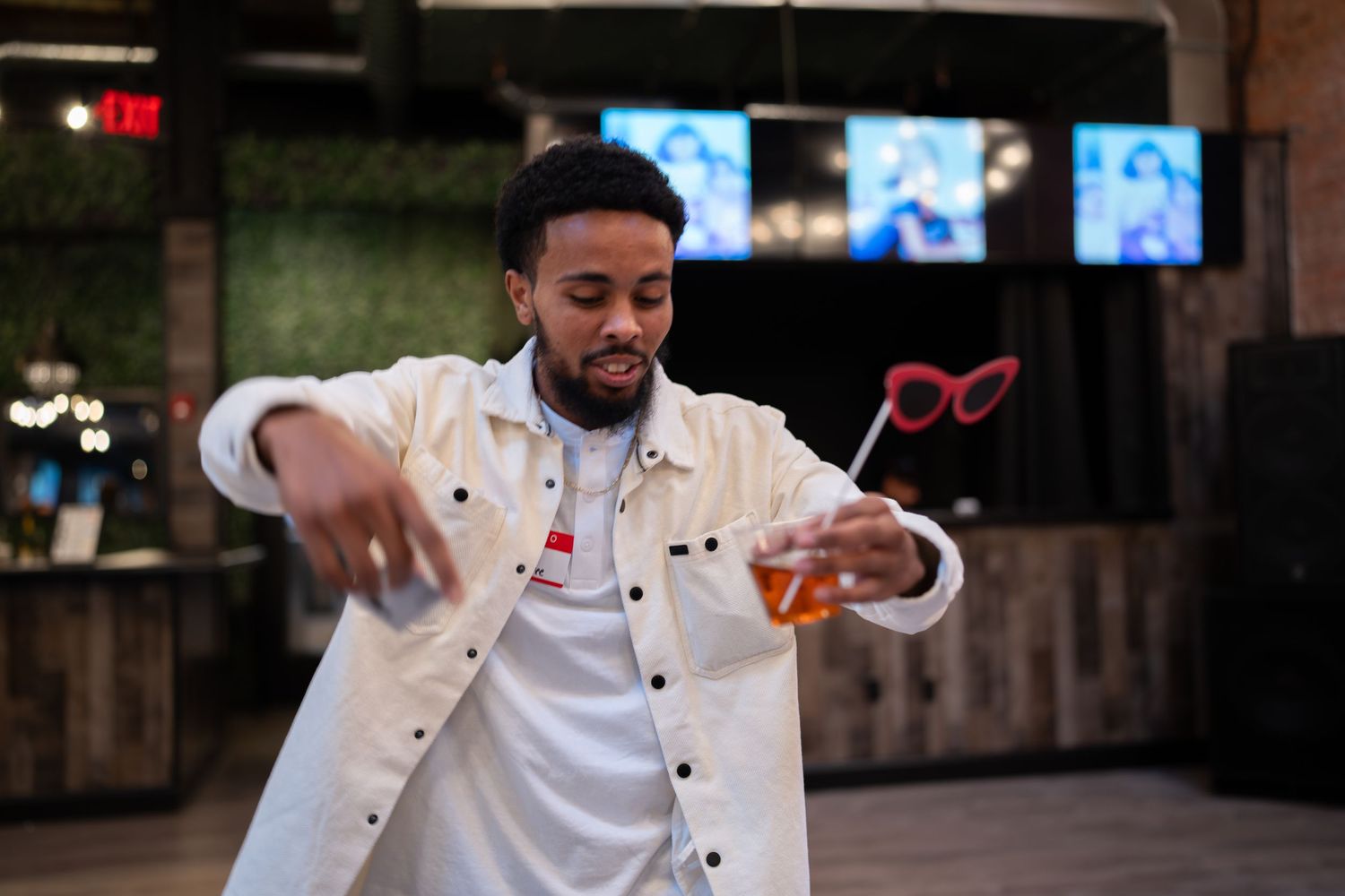 Man in white jacket dancing and holding a drink with fun red glasses prop.